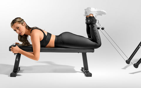 Tonal coach Ash Wilking performing a prone bench hamstring curl on Tonal using ankle straps.