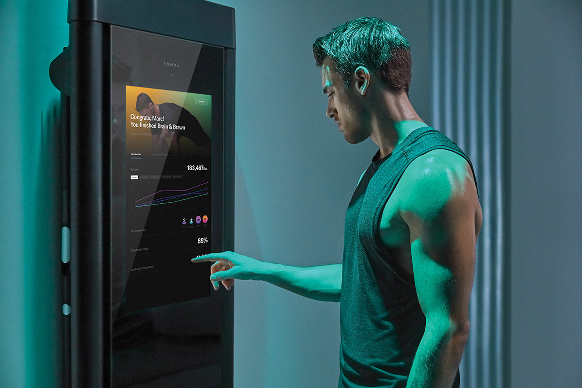 Man in workout clothes reviewing a Tonal workout summary