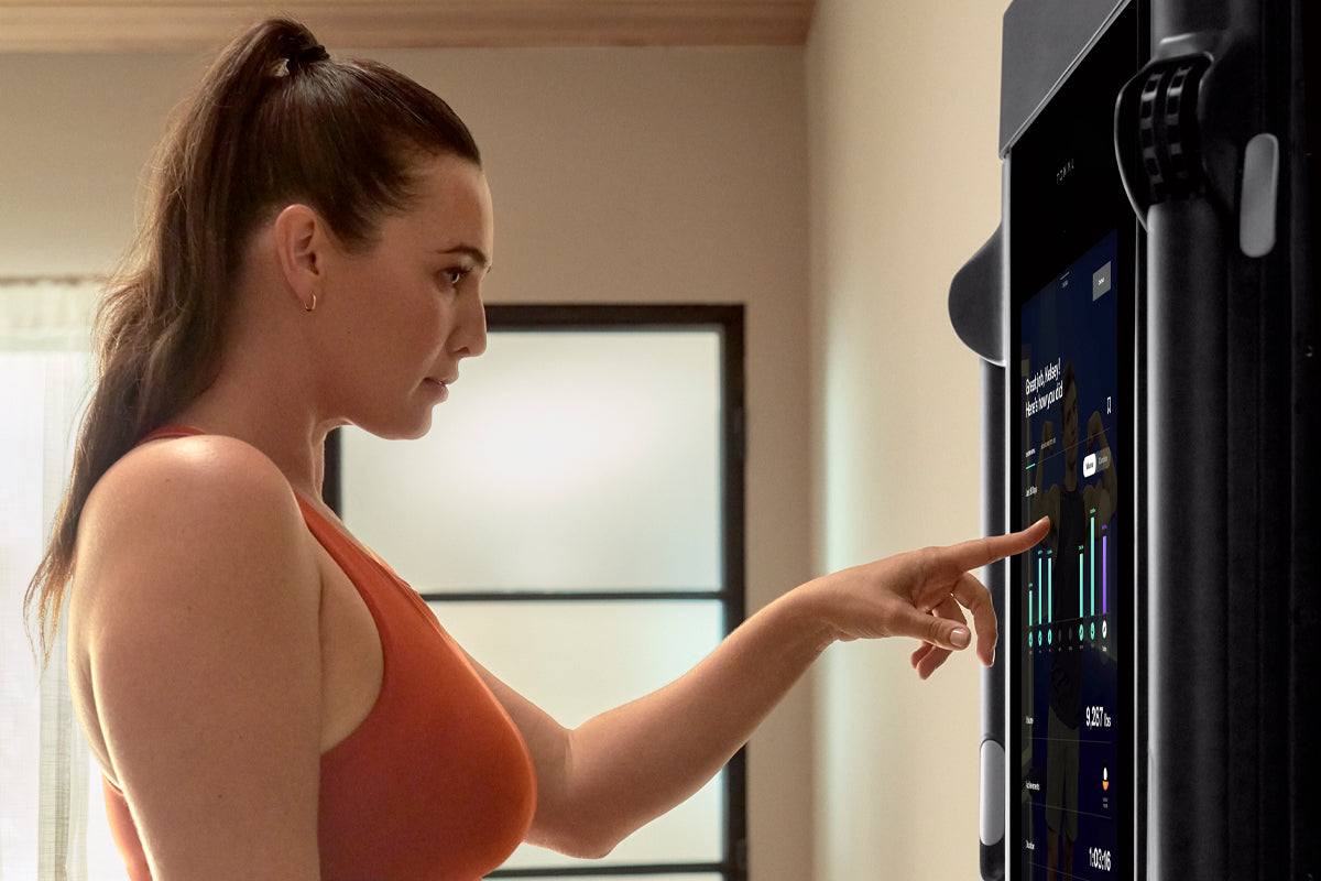 Woman interacting with Tonal's touchscreen.