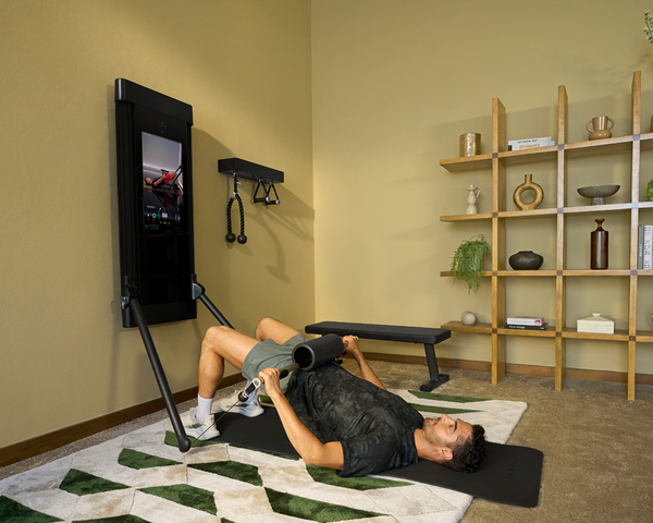 Person doing glute bridge using a Tonal machine in their home