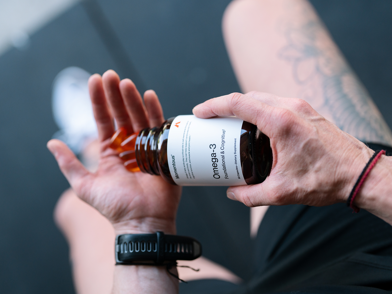 Person taking Momentous Omerga-3 capsules out of container