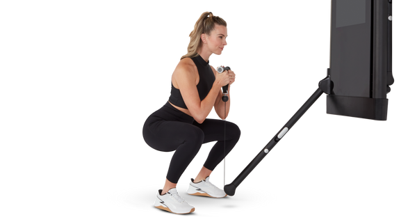 Woman performing goblet squat using Tonal machine and smart handle
