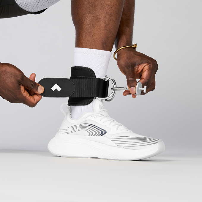 Person putting on Tonal ankle strap attachment