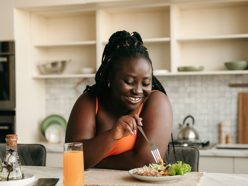 Woman enjoying a salad and juice in kitchen 
